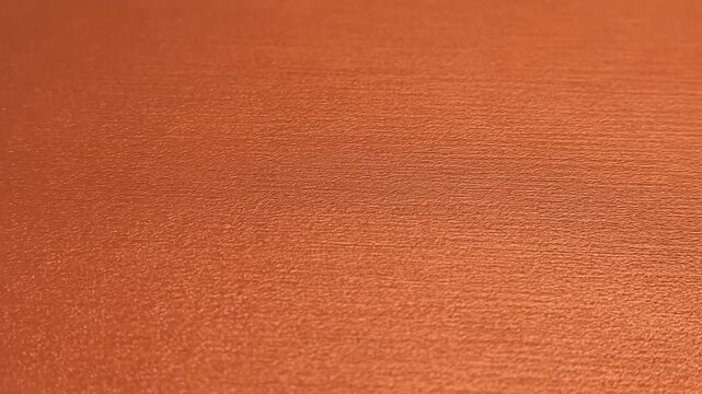 Orange granular liquid forming celllike patches on grey rippled metal surface