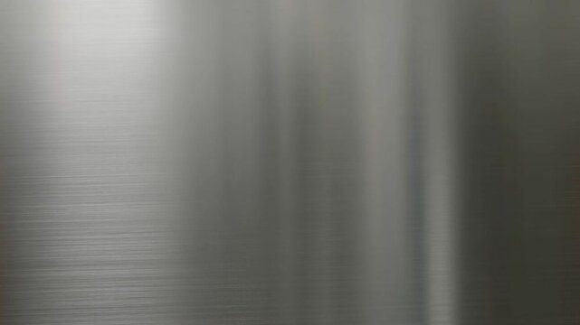Brushed metal surface with light reflections and fine linear grain texture across the frame