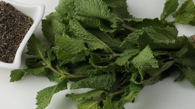 Bunch of fresh green mint and dried herbal flakes isolated on white background