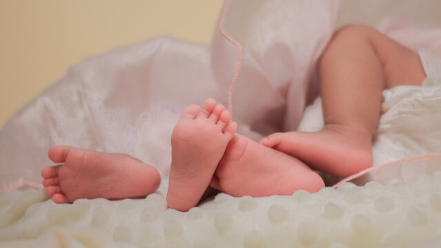 Infant care, feet twin baby, childs, tenderness, family bonding, and early childhood. Close up of newborn baby feet gently supported by an adult hand, with soft natural light and pastel colors.