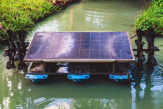 Floating solar powered water aerator paddle wheel in canal. Solar powered floating water aerator with paddle wheels on canal to improve water quality and oxygen levels using renewable green energy.