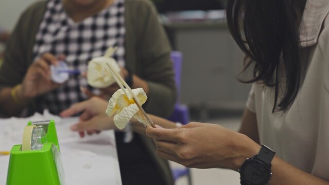 Close-up of a Thai woman making artificial sandalwood paper flowers by hand. Dok Mai Chan is a symbol of mourning and respect used in traditional Buddhist cremation