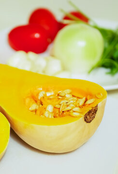 Close up of halved butternut squash with fresh cooking ingredients