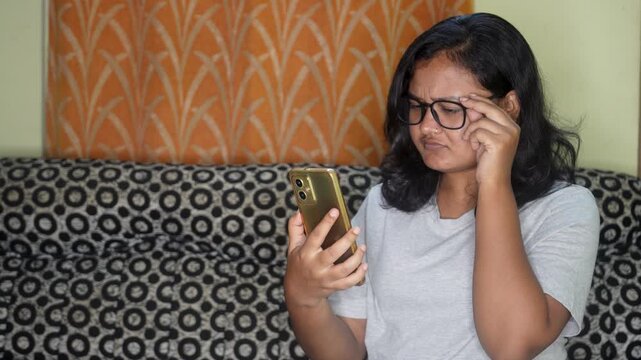 Young woman wearing eyeglasses trying to read message on his smartphone having farsightedness eye disease. female person with presbyopia looking at mobile phone screen. Vision problems concept