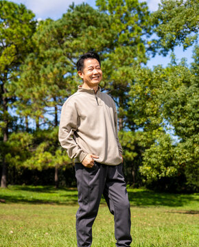 Outdoor portrait of friendly middle age asian male, relaxed casual outfit on sunny day