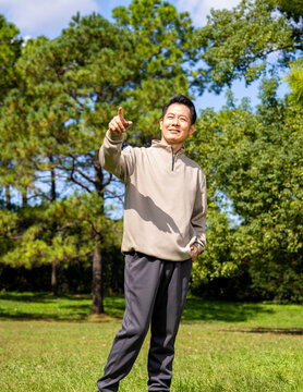 Outdoor portrait of friendly middle age asian male, relaxed casual outfit on sunny day