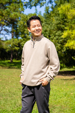 Outdoor portrait of friendly middle age asian male, relaxed casual outfit on sunny day