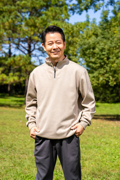 Outdoor portrait of friendly middle age asian male, relaxed casual outfit on sunny day