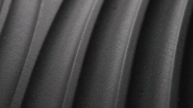 Abstract dark black textured surface with diagonal parallel ridges and waves