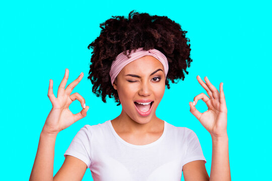 Close up photo beautiful amazing she her dark skin lady winking eye hold hand arm okey symbol toothy approve advising news wear head scarf casual white t-shirt isolated pink bright vibrant background