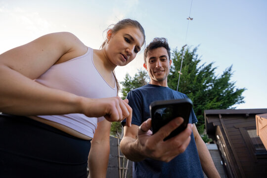 Couple trains in backyard while checking phone together