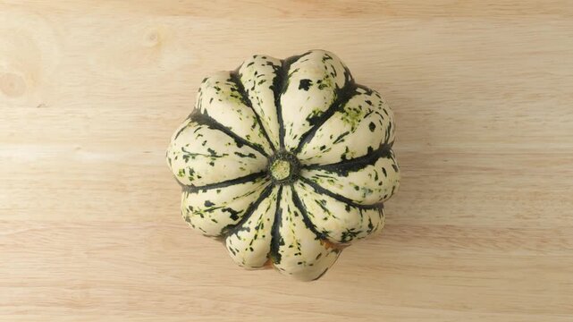 Striped sweet dumpling squash rotating on wooden surface