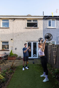 Couple workout in backyard with weights and camera