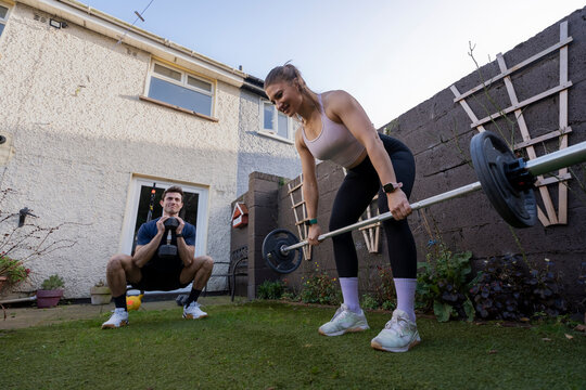 Couple trains together in backyard with weights and fitness gear
