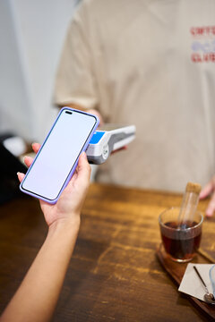 Customer paying contactless with mobile phone at coffee shop