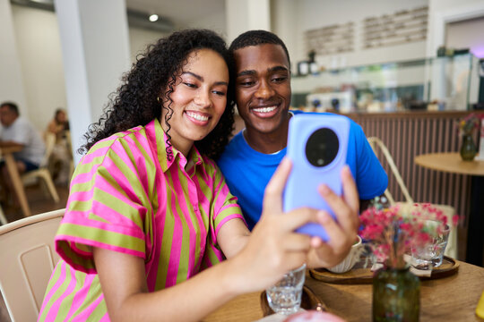 Diverse couple taking a selfie with smartphone in cafe