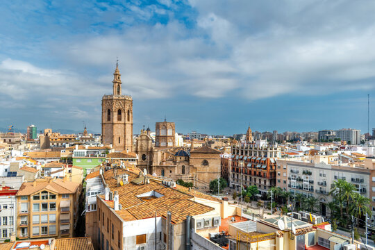 Beautiful cityscape and aerial view of the historic downtown of Valencia, Spain, featuring the iconic Cathedral and El Micalet bell tower under a blue sky with clouds.