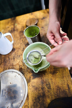 Hands sifting matcha green tea powder into a bowl