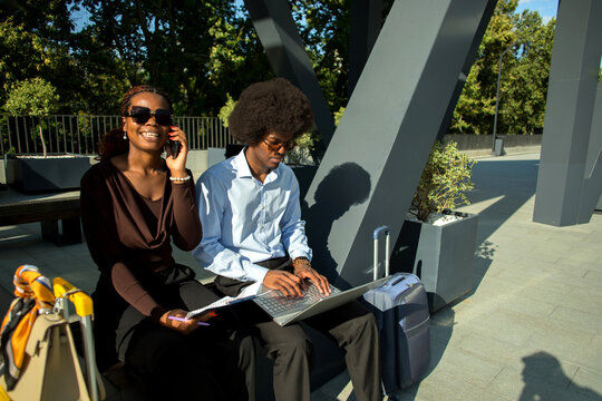 Two Black business professionals working together outdoors.