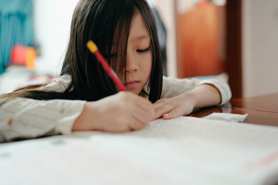 Young Girl Writes on Paper at Home During Daytime