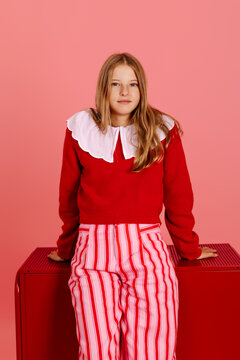 Girl posing with red sweater and striped pants