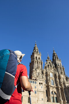 pilgrim with backpack looking at santiago de compostela cathedral from obradoiro square. Copy space
