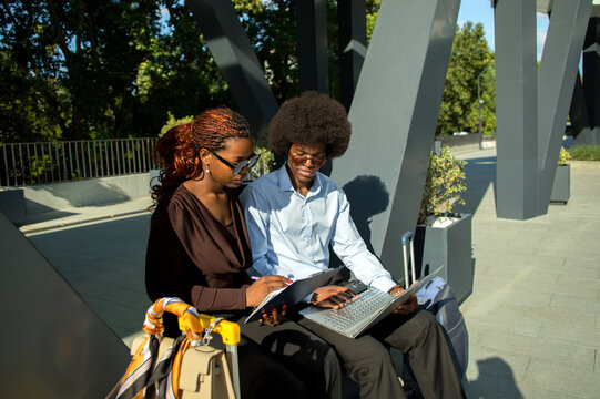 Two Black business professionals working together outdoors.