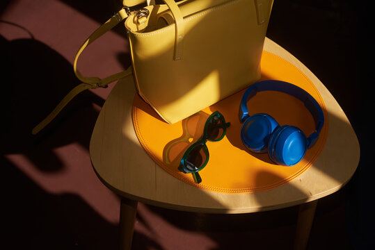 Sunglasses, headphones and leather bag placed on a small table at home