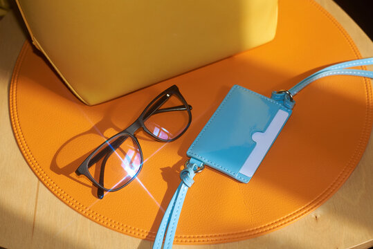Glasses, wallet and bag placed on a orange placemat