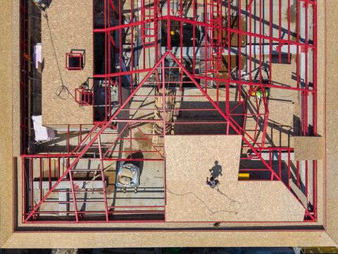 Aerial View Of Red Steel Roof Truss Framing And OSB Panels