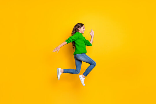 Full body profile side photo of positive cheerful  model kid jump run fast speedy after black friday bargains wear red stylish pullover denim jeans white sneakers isolated over yellow color background