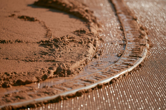 Macro view of brown sludge flowing across stainless steel mesh belt, with glistening water droplets and bright industrial texture creating clean space for environmental engineering imagery