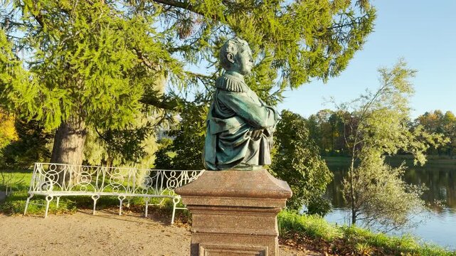 Smooth cinematic camera rotation around a bronze bust in Catherine Park, Pushkin, Saint Petersburg. Circular orbit shot on stabilizer, slow motion, evoking serene tranquility.