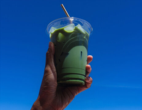 Clear iced matcha cup mockup held against blue sky