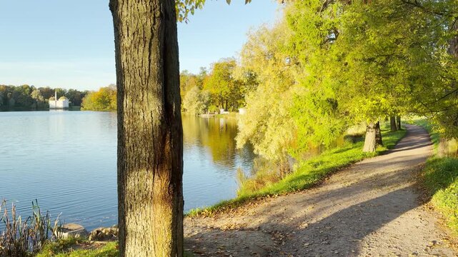 Smooth forward motion captures the scenic lake path in Catherine Park, Pushkin, Saint Petersburg. This POV walkthrough brings a peaceful, serene feeling with no people.