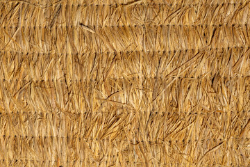 Woven natural straw fiber texture macro surface with stitched horizontal thread lines © brovarky
