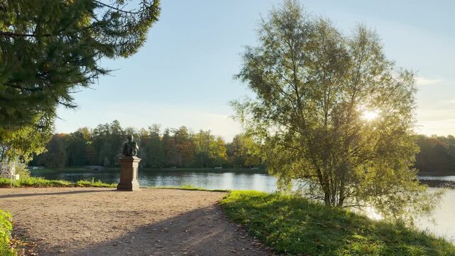 A park monument stands along the lake in Catherine Park, Pushkin, Saint Petersburg. Gentle sunlight illuminates the peaceful landscape, inspiring calm and joy.