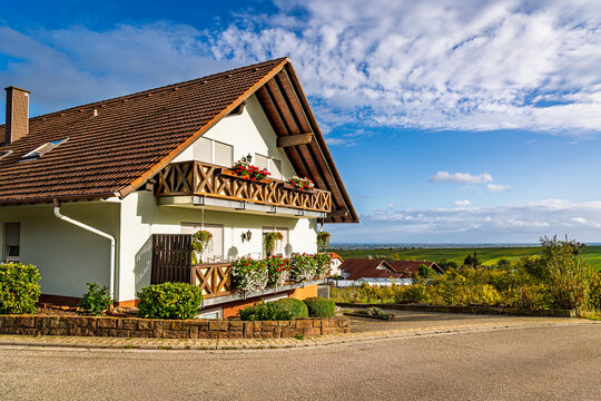 House with wooden balconies beside a country road in a rural village during daytime