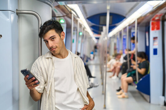 Young man using phone commuting on subway train