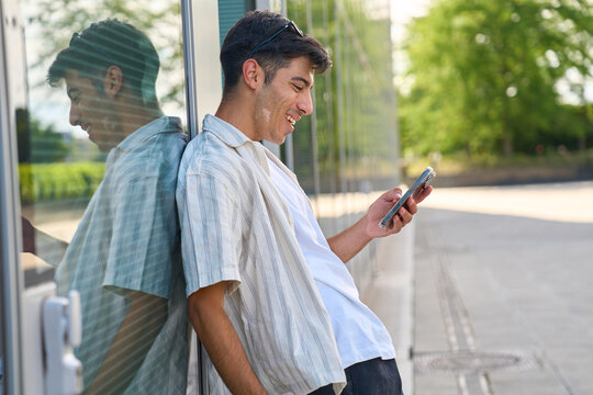 Young man smiling using smartphone outdoors urban