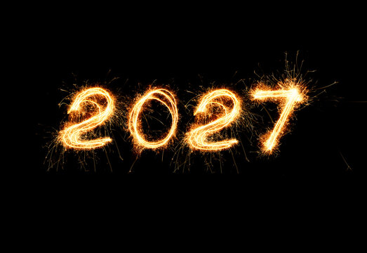 Happy New Year 2027 written with sparkler fireworks on black background. Bright golden light burning number 2027 with sparks for holiday party, greeting card, web banner, and festive design.
