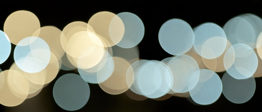 Large defocused gold and pale blue circular bokeh lights on a black panoramic festive background