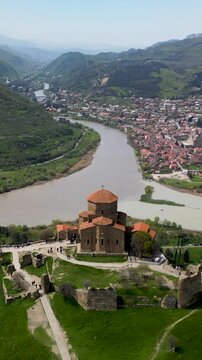 Vertical drone footage of Jvari Monastery overlooking the confluence of the Aragvi and Mtkvari rivers and the historic town of Mtskheta, Georgia.