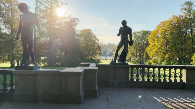 Tracking shot of an empty terrace with statues on gimbal. Smooth sideways camera movement reveals golden autumn in Catherine Park, Pushkin, Saint Petersburg, evoking deep peace.