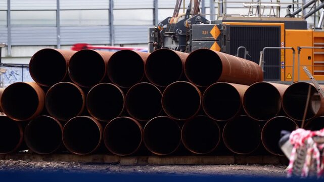 Large diameter steel pipes stacked at an industrial construction site, illustrating pipeline infrastructure, heavy construction materials, utility engineering and industrial supply logistics
