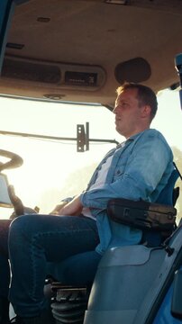 Man farmer puts cap on dashboard inside combine harvester cabin
