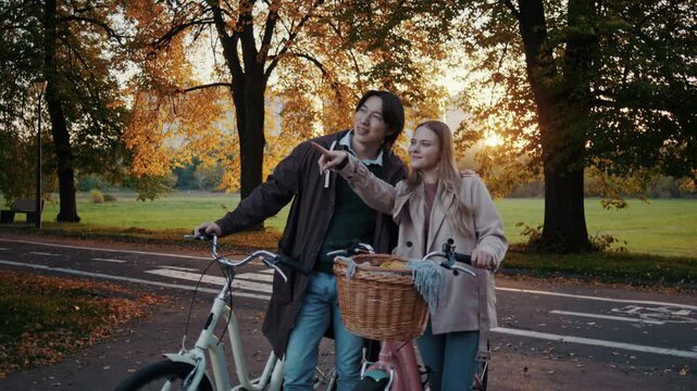 Couple pauses with bicycles during golden autumn park walk