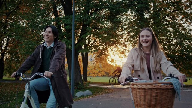 Smiling couple rides bicycles together during autumn sunset