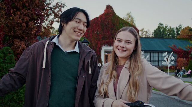 Happy couple smiles at each other during autumn park walk