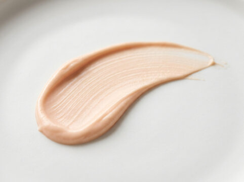 Close-up macro shot of a cosmetic foundation makeup cream smear on a white surface